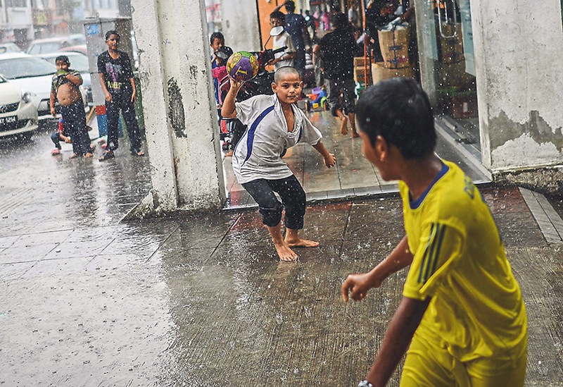 Children of the Rohingya community in Kuala Lumpur play in the rain.