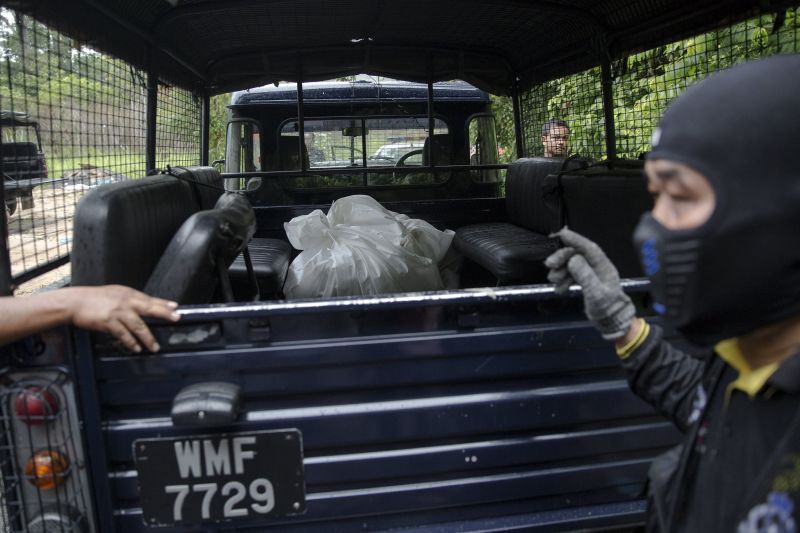 A police forensic team transport body bags with human remains dug from the grave near the abandoned human trafficking camp in the jungle close the Thailand border at Bukit Wang Burma in northern Malaysia May 27, 2015. u00e2u20acu2022 Reuters pic