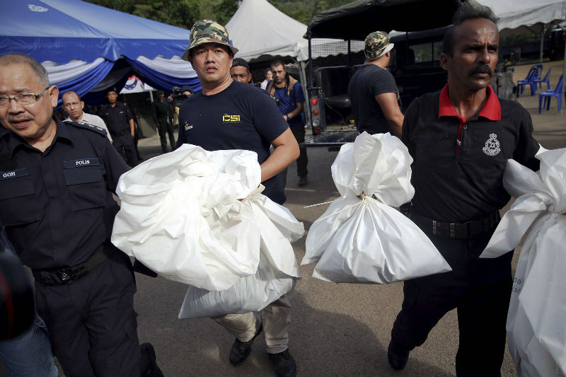 Forensic policemen carry body bags with human remains found at the site of human trafficking camps in the jungle close the Thailand border after they brought them to a police camp near Wang Kelian May 25, 2015. — Reuters pic