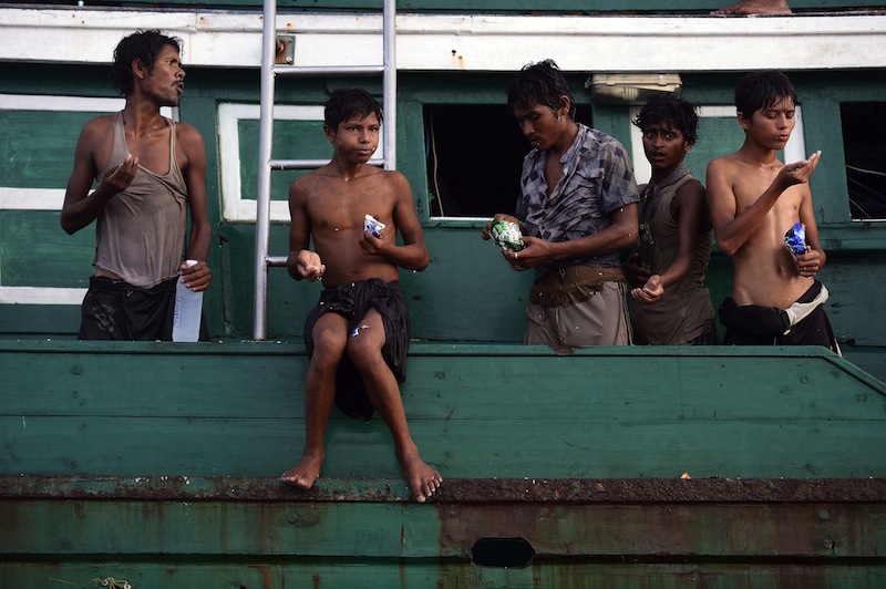 Rohingya migrants eat food supplies dropped by a Thai army helicopter after collecting them at sea as they stand on a boat drifting in Thai waters off the southern island of Koh Lipe in the Andaman sea on May 14, 2015. u00c2u00a0u00e2u20acu201d AFP pic