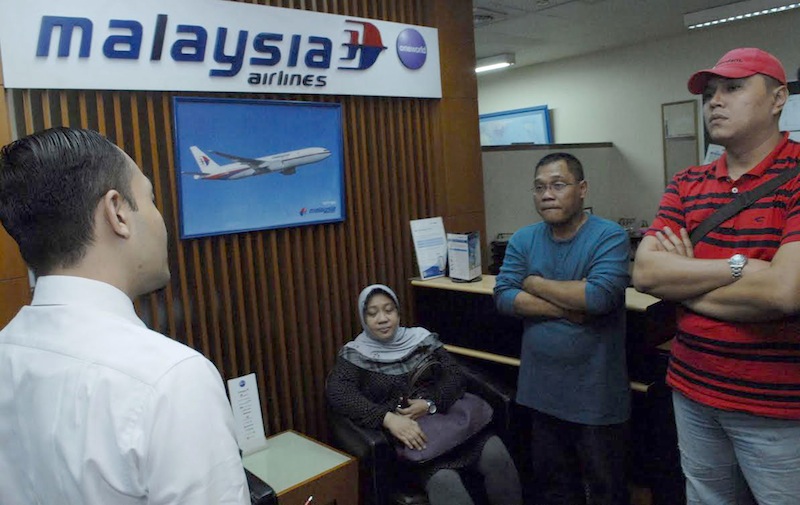 A staff member (left) at the Malaysia Airlines branch office at Jakarta International airport helps relatives with information on July 18, 2014.u00c2u00a0u00e2u20acu201d AFP pic