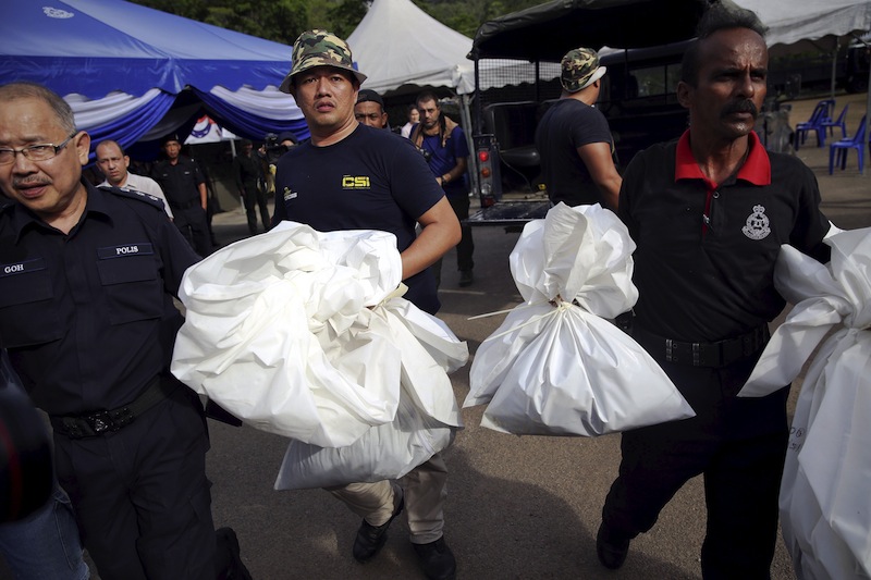 Forensic policemen carry body bags with human remains found at the site of human trafficking camps in the jungle close the Thailand border after they brought them to a police camp near Wang Kelian in northern Malaysia May 25, 2015.u00c2u00a0u00e2u20acu201du00c2u00a0Reuters pic