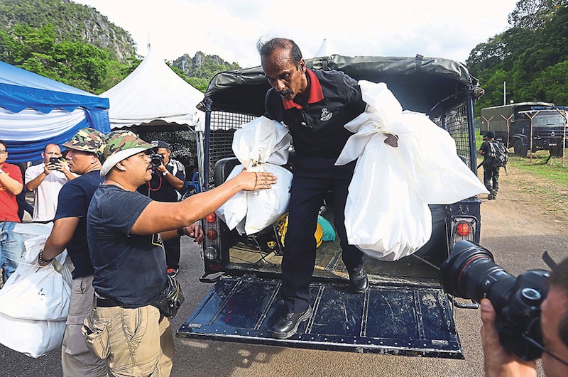 Police officers unloading plastic bags containing body parts of three victims. u00e2u20acu201d Picture by Sayuti Zainudin