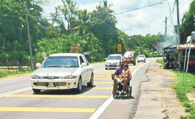 Rosli sending his son to school along a busy street. u00e2u20acu201d Pix by Tony Mariadass and Jason Wee