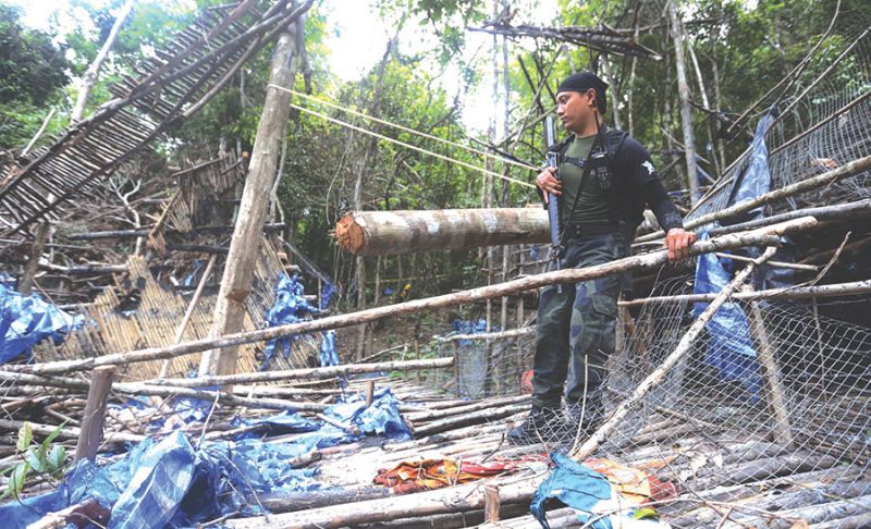 A security personnel looking at whatu00e2u20acu2122s left of an immigrant camp at Bukit Wang Burma, near the Malaysia-Thailand border recently. u00e2u20acu201d Picture by Sayuti Zainudin
