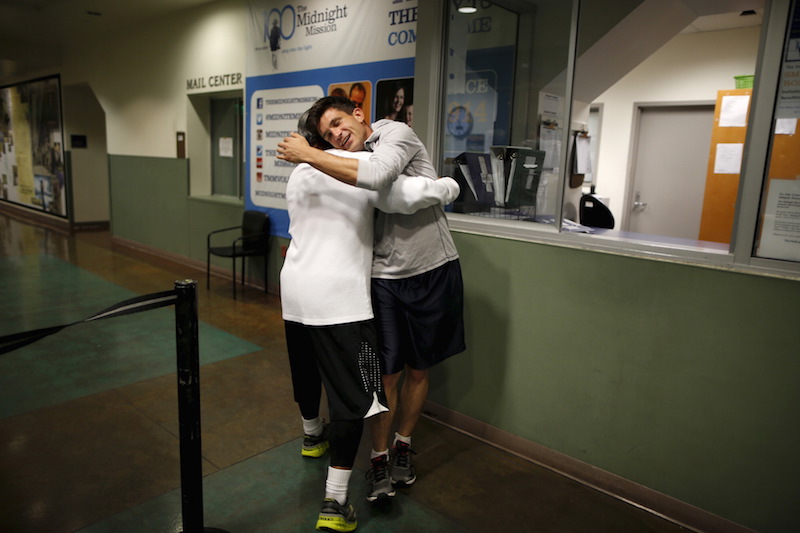 Runners from the Midnight Mission Running Club Seth Becker and Oscar Knight greet each other before beginning a sunrise run through Skid Row in Los Angeles April 20, 2015. — Reuters pic