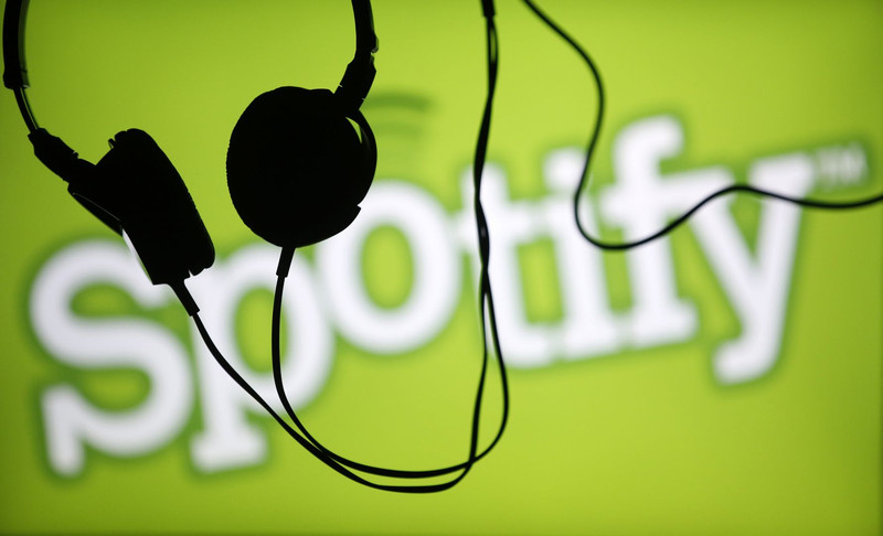Headsets hang in front of a screen displaying a Spotify logo on it. u00e2u20acu201d File pic 