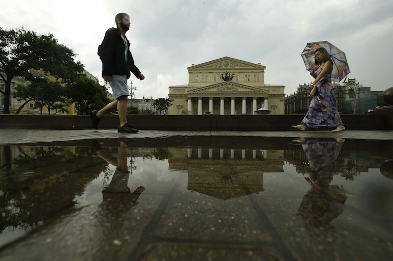 People walk through a rain, shower with the Bolshoi Theatre seen in the background, in central Moscow, Russia, May 29, 2015. u00e2u20acu201du00c2u00a0Reuters pic