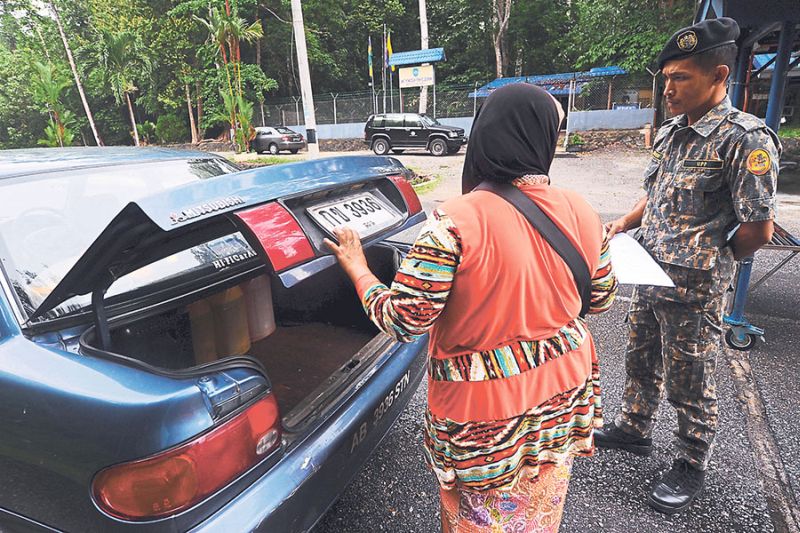 An Anti-Smuggling Unit (UPP) officer checks a car near Wang Kelian in Perlis. u00e2u20acu201d Picture by Azinuddin Ghazali
