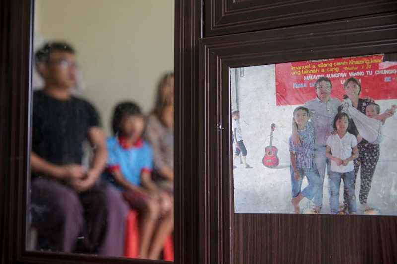 An old picture of the family is pasted on the wooden closet in their rented room.