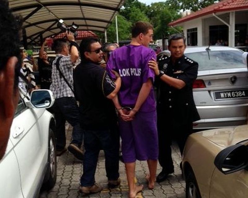 One of the four tourists being led away by the police at the Kota Kinabalu court today. ― Picture by Julia Chan