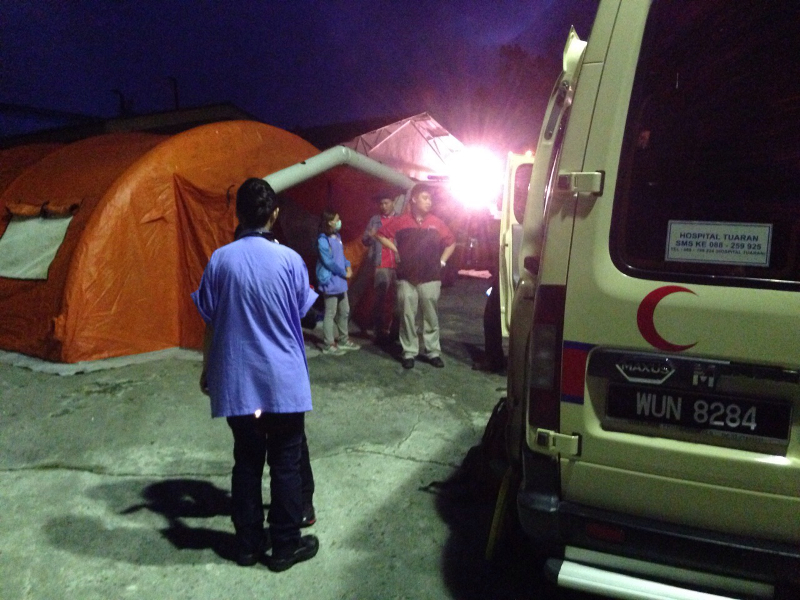 An ambulance and medical personnel are on standby at Mount Kinabalu's base camp as darkness falls.