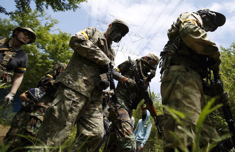 Participants of a ‘survival game’ holding their air guns manoeuvre during their game at a field in Chiba, Japan, June 11, 2015. — Reuters pic