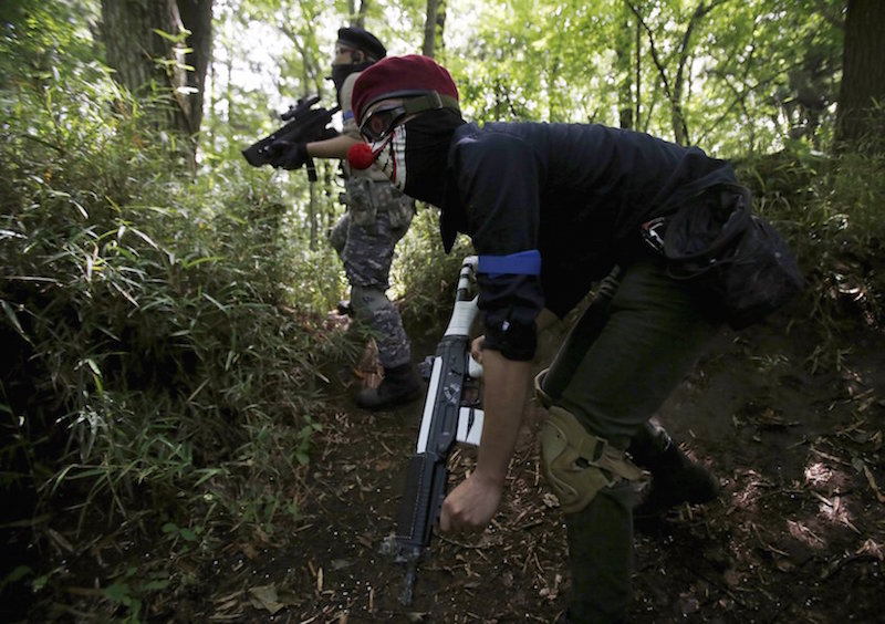 A participant of a ‘survival game’ wearing a face mask holds his air gun as he manoeuvres during his game at a field in Chiba, Japan, June 11, 2015. — Reuters pic