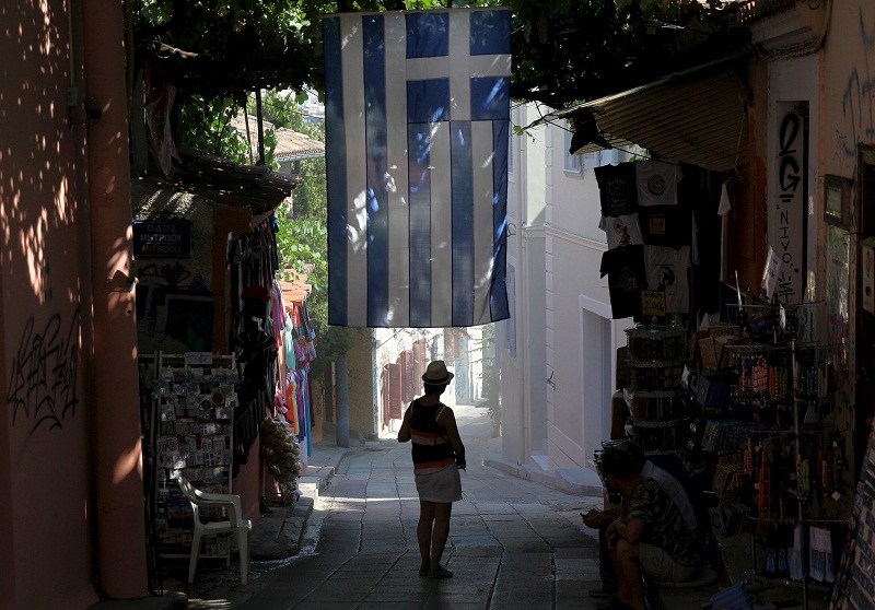 A tourist stands under a Greek national flag at the Monastiraki area in Athens, Greece July 15, 2015. u00e2u20acu201d Reuters pic