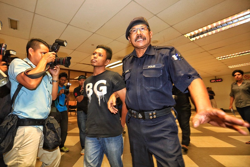 The alleged thief at Low Yat Plaza last weekend, Shahrul Anuar Abdul Aziz (centre), is escorted by a police officer in Kuala Lumpur on July 14, 2015. u00e2u20acu2022 Picture by Saw Siow Feng