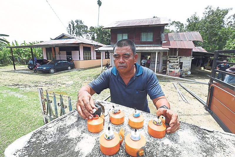 Abdul Talib places oil lamps on the gate of his house ahead of Hari Raya. u00e2u20acu201d Picture By Farhan Najib