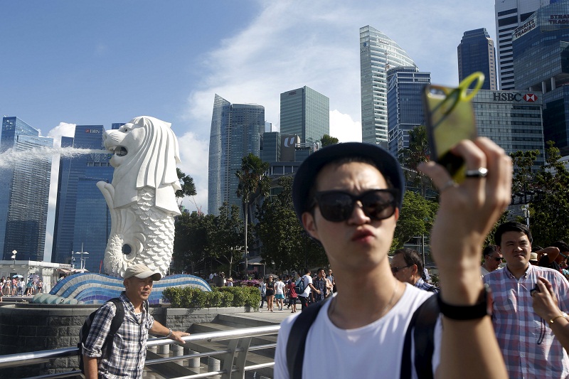 Tourists pose for selfies and photos with the statue of a Merlion along Marina Bay near the skyline of the central business district in Singapore. Picture released July 31, 2015. u00e2u20acu201d Reuters pic