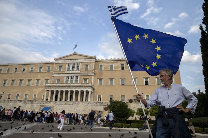 A pro-Euro protestor holds a European Union flag with a Greek national flag on top during a rally in front of the parliament building in Athens, Greece, June 30, 2015. REUTERS