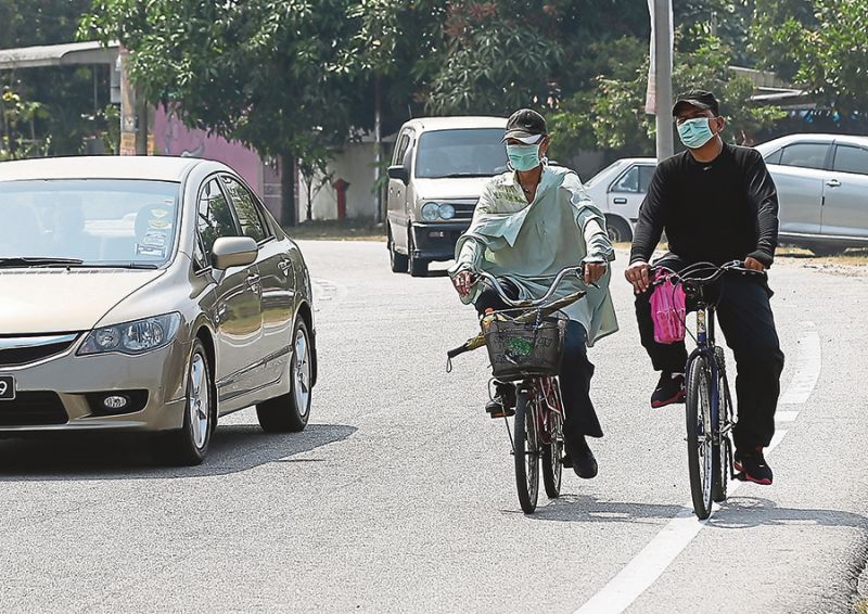 Two cyclists go about their business in Simee, Ipoh, wearing face masks. The dry spell in the last two weeks has aggravated the quality of air in the city. u00e2u20acu201d Picture by Marcus Pheong