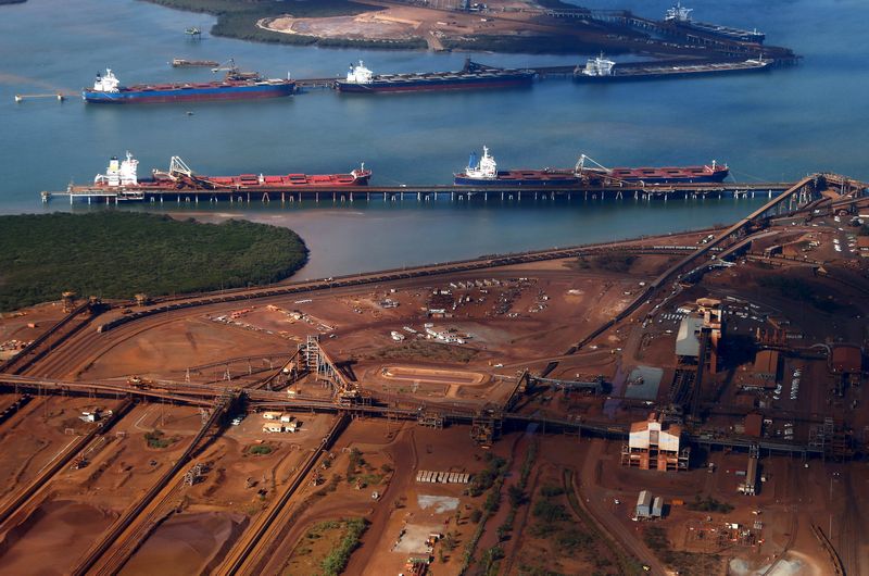 Ships waiting to be loaded near piles of iron ore at Port Hedland, Western Australia, December 3, 2013. Iron ore prices will decline by an average 40 per cent in 2015. u00e2u20acu201d Reuters pic