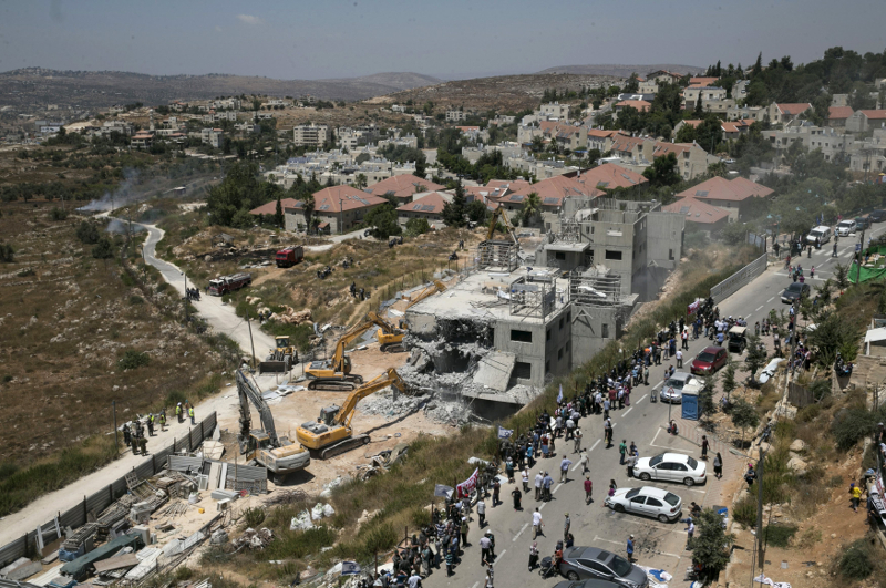 Israeli paramilitary police and Jewish settlers stand near two partially-built dwellings during their demolition in the West Bank Jewish settlement of Beit El near Ramallah July 29, 2015. u00e2u20acu201d Reuters pic
