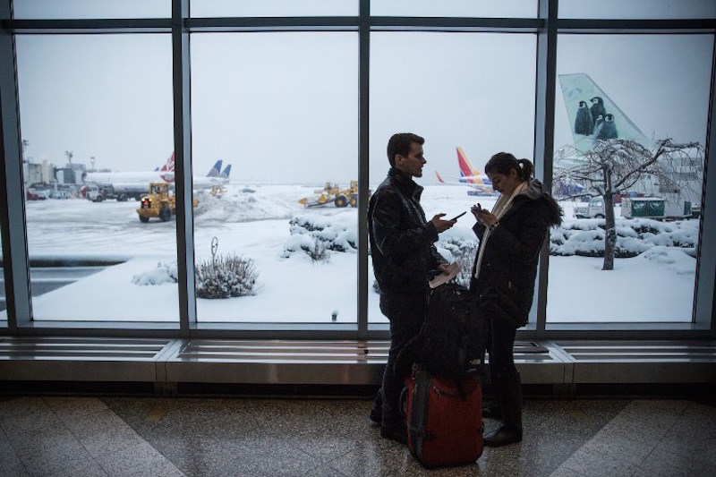 Travellers check their phones while waiting for their flight at La Guardia Airport in the Queens borough of New York City February 2, 2015, during a winter storm. u00e2u20acu201d AFP pic