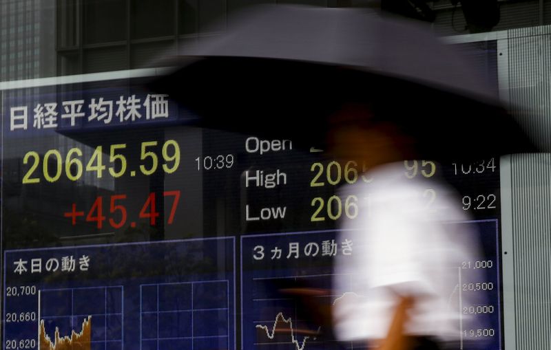 A man walks past a board displaying the Nikkei average in Tokyo July 17, 2015. Asian shares edged up on Tuesday, July 21, 2015. u00e2u20acu201d Reuters pic