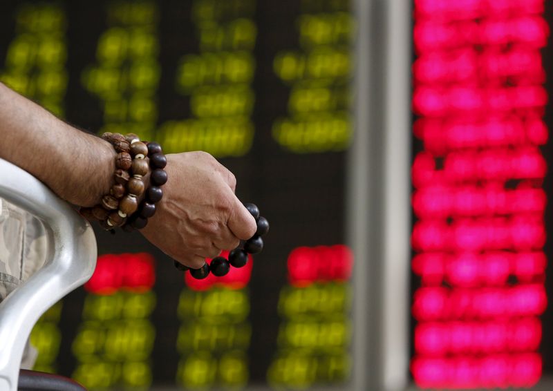 An investor holds onto prayer beads as he watches a board showing stock prices at a brokerage office in Beijing, China, in this July 6, 2015 file photo. u00e2u20acu201d AFP pic