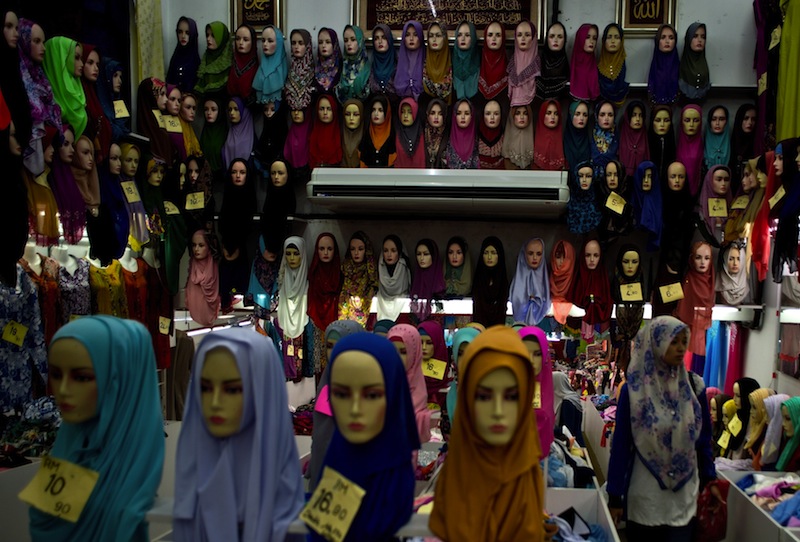 A Malaysian woman walks past mannequins displaying traditional head scarves or tudung at a Ramadan market ahead of the Eid al-Fitr festival in Kuala Lumpur on July 12, 2015.u00c2u00a0u00e2u20acu201du00c2u00a0AFP pic