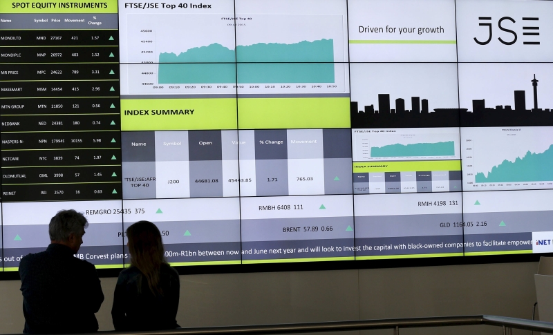 People chat in front of an electronic board displaying movements in major indices at the Johannesburg Stock Exchange building in Sandton Johannesburg July 9, 2015. u00e2u20acu201d Reuters pic