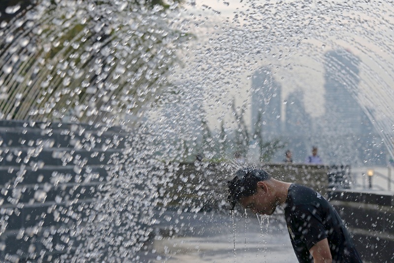 A youth cools himself off at a water fountain near Marina Bay in Singapore July 27, 2015. — Reuters pic