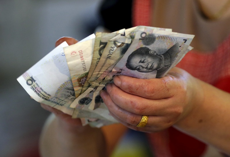 A vendor holds Chinese yuan notes at a market in Beijing in this August 12, 2015 file photo. u00e2u20acu201d Reuters pic