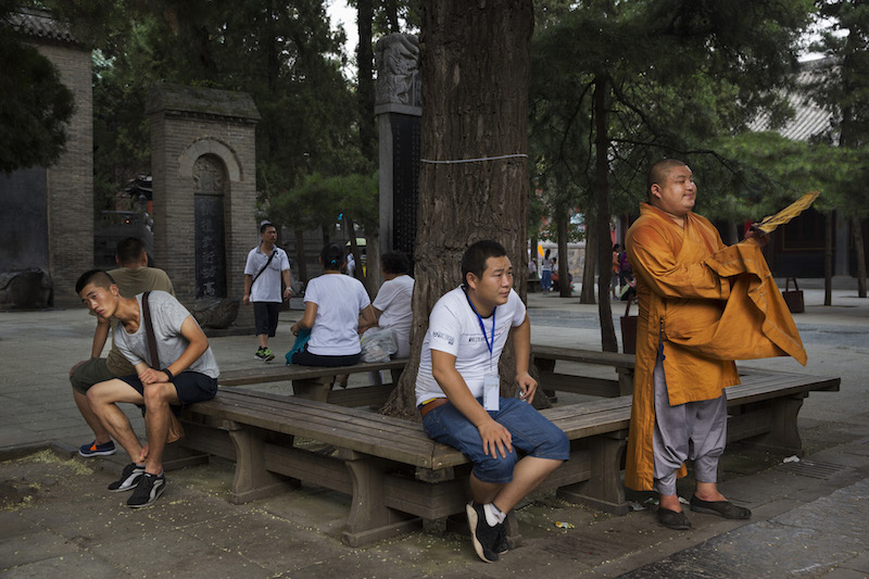 A monk, right, stands among tourists at the Shaolin Temple in Dengfeng, China, July 31, 2015. — Picture by Adam Dean/The New York Times