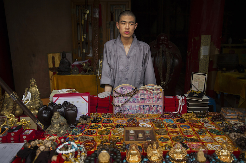 A monk sells souvenirs and religious trinkets at the Shaolin Temple in Dengfeng, China, July 31, 2015. — Picture by Adam Dean/The New York Times