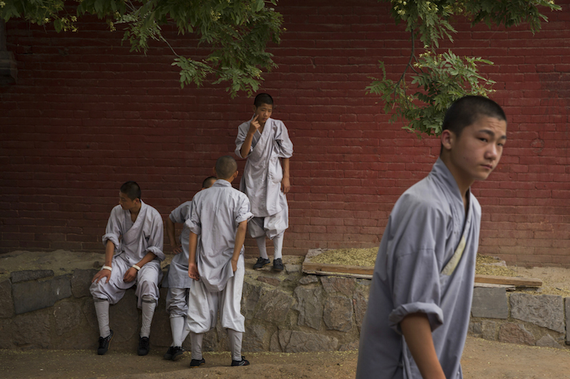 Monks talk together outside before a kung fu performance at the Shaolin Temple in Dengfeng, China, July 31, 2015. — Picture by Adam Dean/The New York Times