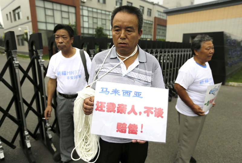 A man, whose relative was aboard Malaysia Airlines flight MH370, holds a placard with strings around his neck during a protest ahead of a briefing given by Malaysia Airlines, in Beijing August 7, 2015. u00e2u20acu201du00c2u00a0Reuters pic