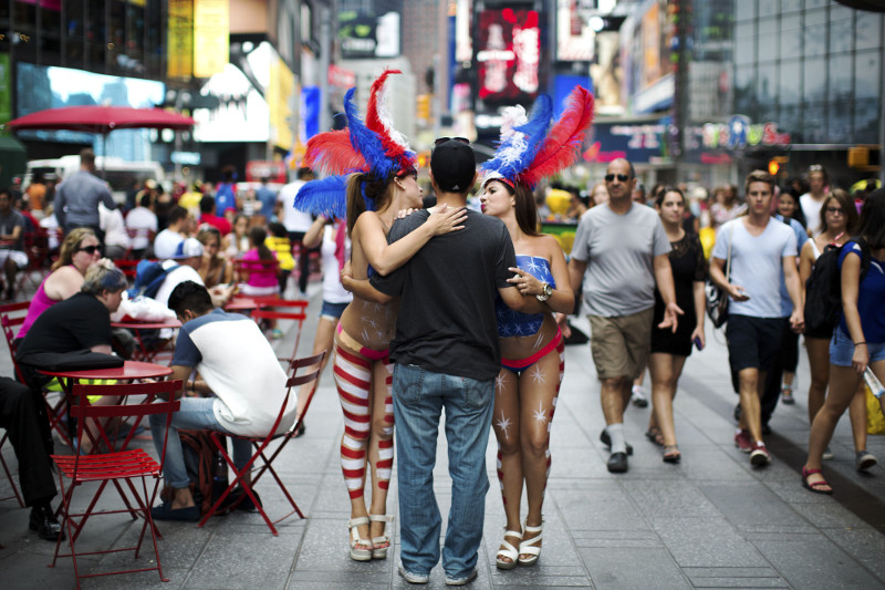 Paola Pena, left, and Mey Ovalles, right, pose for a photograph with a man in exchange for tips at Times Square in New York, August 5, 2015. u00e2u20acu201d Picture by Hilary Swift/The New York Times