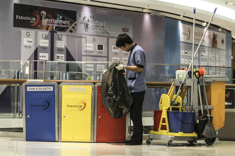 A cleaner sorts through waste at the recycling bins at Paradigm Mall in Petaling Jaya. — Picture by Yusof Mat Isa