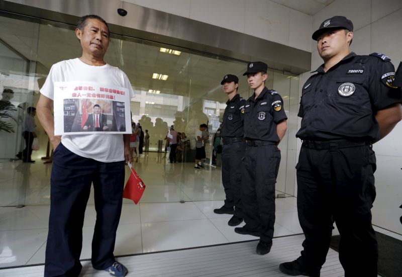 Zhang Yongli, whose daughter was aboard MH370, stands next to security guards as he and other family members express their demands to Malaysia Airlines outside its Beijing office August 6, 2015. u00e2u20acu2022 Reuters pic 