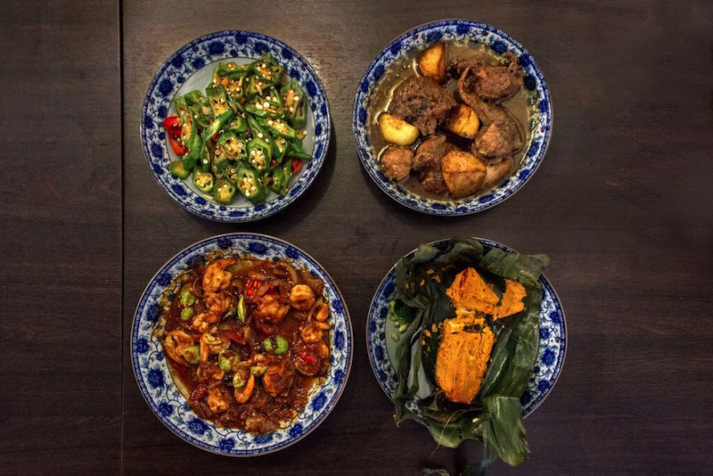 A typical Malaccan Peranakan meal (clockwise from top left): spicy lady's fingers with dried shrimp, ayam pongteh, otak-otak, and sambal petai udang.