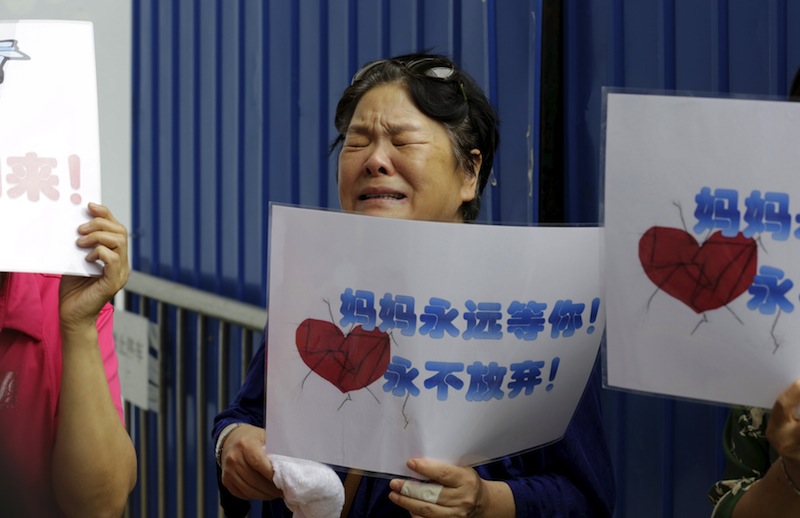 Zhang Meiling, whose daughter and son-in-law were aboard Malaysia Airlines flight MH370, holds a placard reading 'Mom is always here waiting for you, never will give up' in Beijing. u00e2u20acu201d Reuters pic