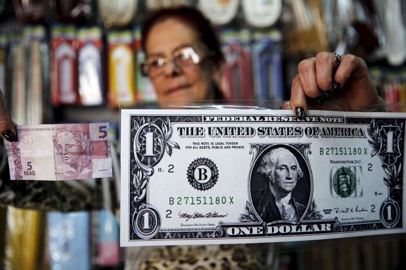 A woman holds a giant US$1 banknote and a five reais banknote inside a shop, in the town of Itu, northwest of Sao Paulo, Brazil, August 8, 2015. ― Reuters pic