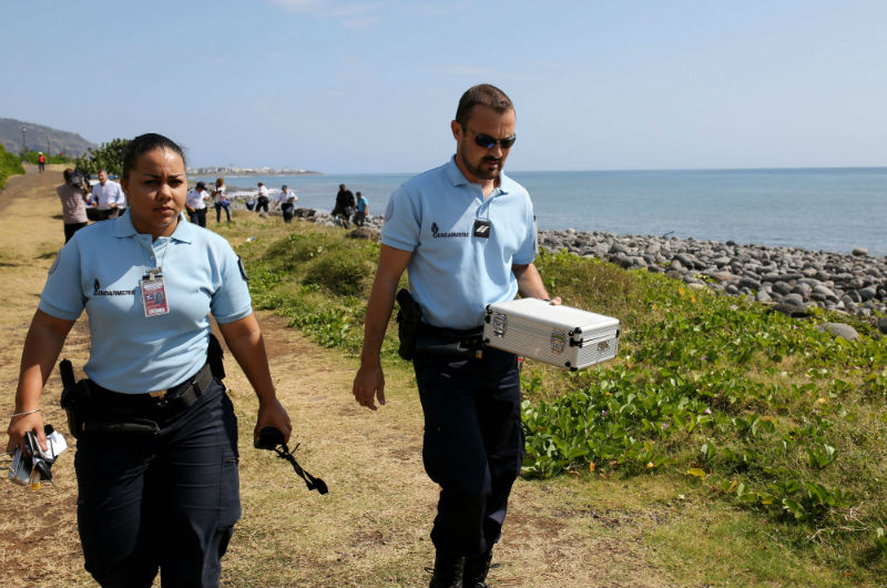 Police officers leave the scene with container holding metallic debris found on a beach in Saint-Denis on the French Reunion Island in the Indian Ocean on August 2, 2015. u00e2u20acu201d AFP pic