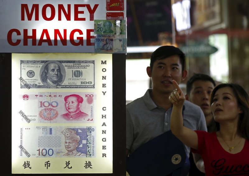People look at the exchange rate at a moneychanger displaying a poster of US dollar bill, Chinese Yuan and Malaysia Ringgit in Singapore August 24, 2015. u00e2u20acu201d Reuters pic