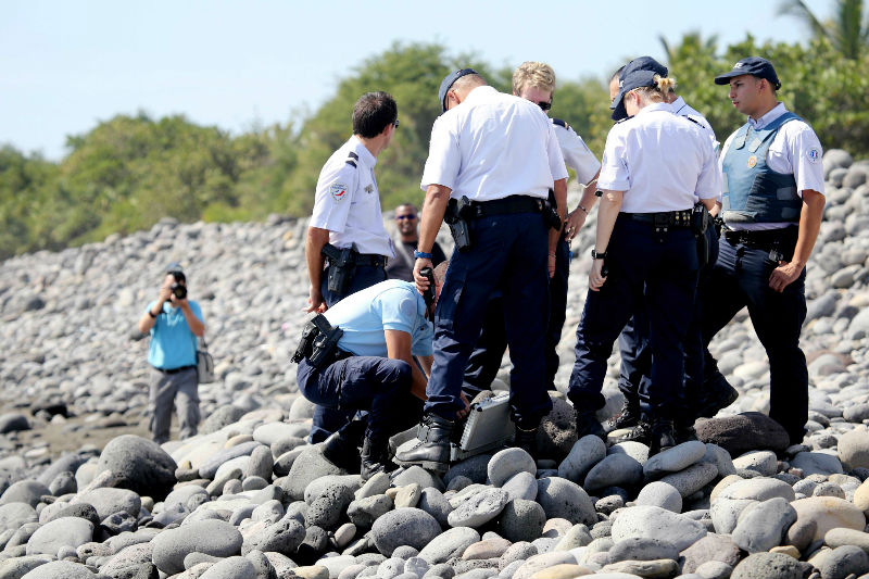 Police officers inspect metallic debris found on a beach in Saint-Denis on the French Reunion Island in the Indian Ocean on August 2, 2015, close to where a Boeing 777 wing part washed up. u00e2u20acu201d AFP pic