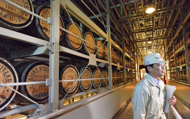 This photo taken on May 13, 2014 shows a worker standing next to casks of whisky at a storehouse of Suntory Liquorsu00e2u20acu2122 Hakushu distillery in Hokuto City, Yamanashi prefecture. u00e2u20acu201d AFP pic