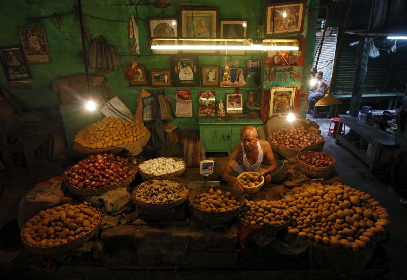 A vendor weighs potatoes for a customer (not pictured) in his shop at a vegetable market in Kolkata, India. u00e2u20acu201d Reuters pic