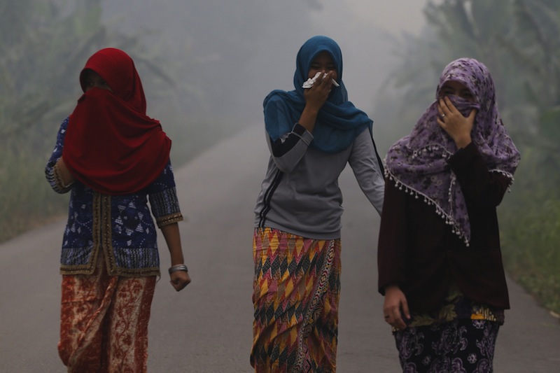 Villagers walk on a street as the haze shrouds Pulau Mentaro village in Muaro Jambi, on the Indonesian island of Sumatra, September 15, 2015.u00c2u00a0u00e2u20acu201du00c2u00a0Reuters pic
