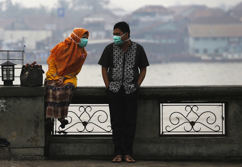 A couple, wearing face masks to protect themselves from the haze, talk near Musi River in Palembang, on the Indonesian island of Sumatra, September 20, 2015.u00c2u00a0u00e2u20acu201d Reuters pic